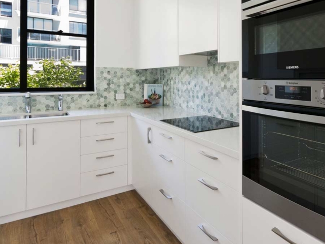 Quantum Quartz stone benchtop in Carrara Quartz. Apartment renovation by Reno Pack featuring Dulux polyurethane cabinets, Westinghouse, Fisher Paykel appliances and Quick Step Impressive Ultra floating floor.